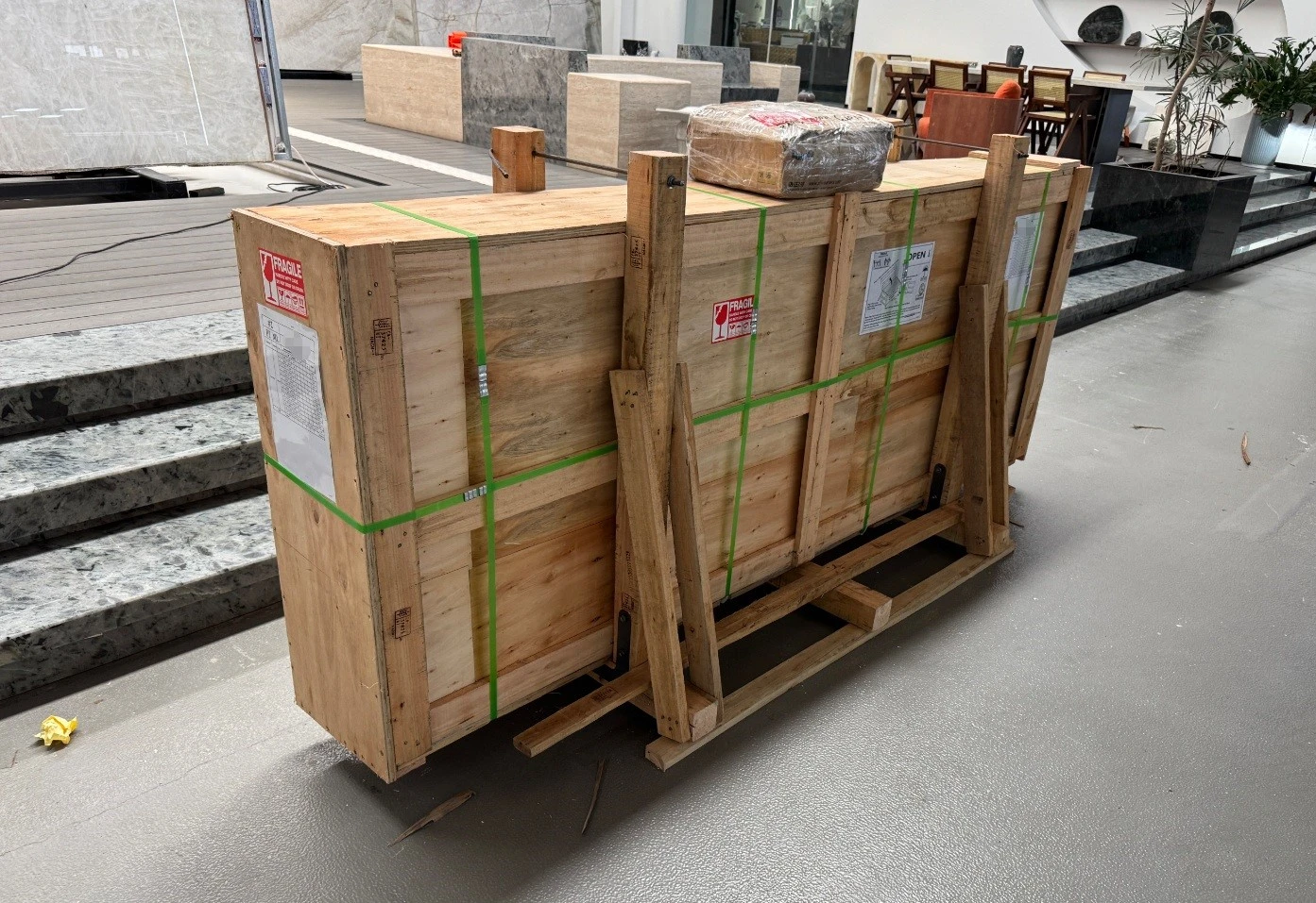 Vanilla Onyx slabs packed vertically in a reinforced wooden export crate with green strapping and fragile labels. Vanilla Onyx slabs packed vertically in a reinforced wooden export crate with green strapping and fragile labels.